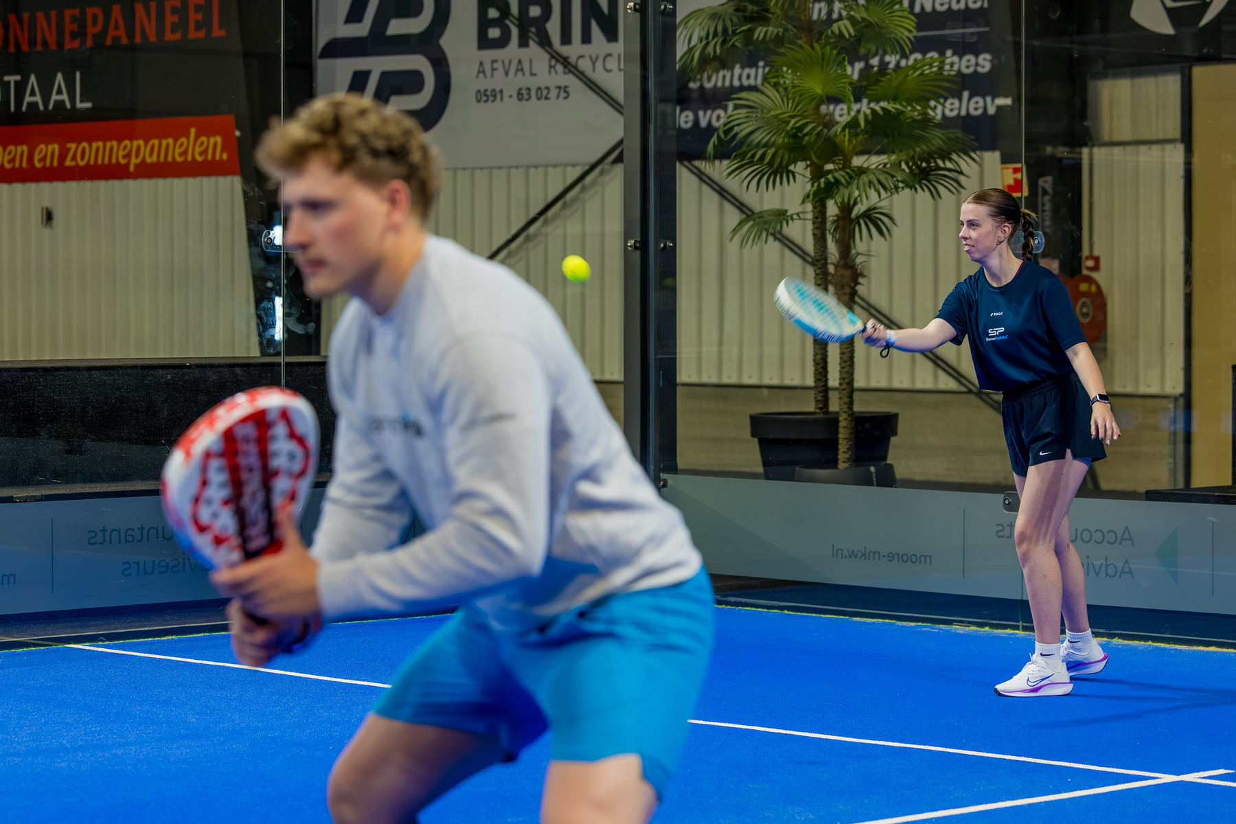 Twee spelers in een rally op de baan bij PadelMM