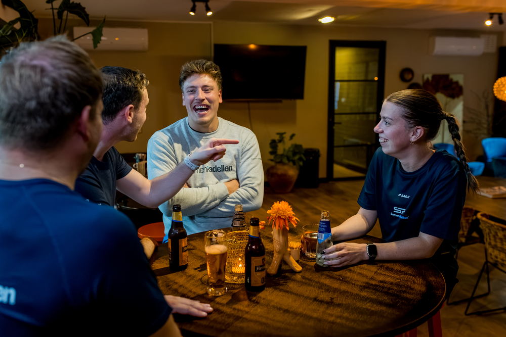Spelers napraten na afloop aan een tafel bij de baan